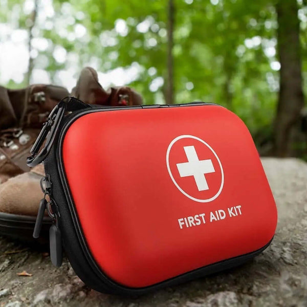 Compact red first aid kit on the ground, ideal for travel, hiking, and emergencies, featuring essential medical supplies.