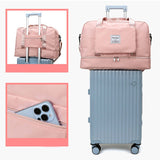 Medium waterproof travel duffel bag in pink on a rolling suitcase, showcasing compartments and phone pocket.