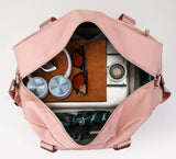 Open medium waterproof travel duffel bag filled with accessories, sunglasses, a notebook, and a camera.